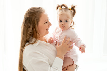 a mother with a baby daughter, a mother gently hugs her baby girl kissing, maternal love and care, a happy family with a baby on a white isolated background, a place for text