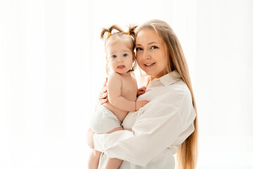 a mother with a baby daughter, a mother gently hugs her baby girl kissing, maternal love and care, a happy family with a baby on a white isolated background, a place for text