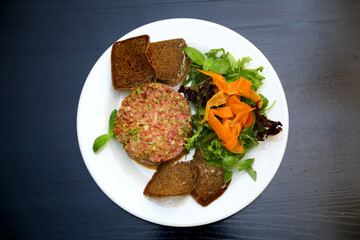 Raw meat tartare for gourmets. Raw meat tartare with spices, croutons and herbs. Beef tartare with capers. Beef tartare with bread slices.