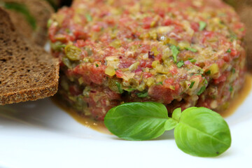 Raw meat tartare for gourmets. Raw meat tartare with spices, croutons and herbs. Beef tartare with capers. Beef tartare with bread slices.