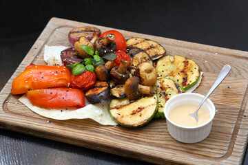 Grilled vegetables with sauce. Baked tomatoes, mushrooms, zucchini, sweet peppers and onions. Grilled vegetables are simply delicious.