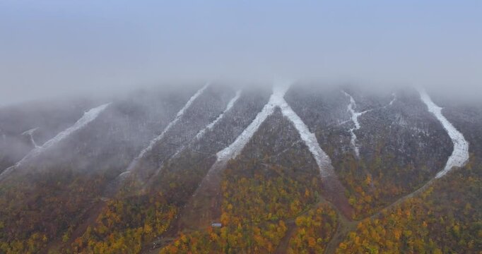 Mountains of Vermont, New England, USA covered with thick fog. A rock is half-covered with colorful woods in autumn. Aerial view.