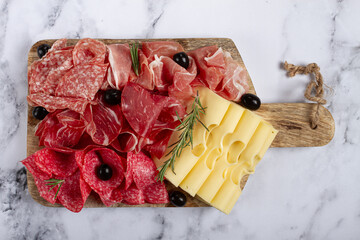 Assorted meat, appetizer, prosciutto, salami and ham, with maasdam cheese and olives, on a wooden...