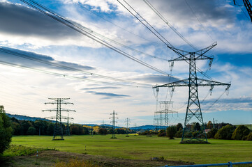 A landscape photo of power lines and transmission towers stretching across an open field with a...