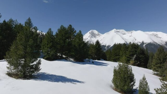 Aerial video over Aramiyska Meadow in Pirin Mountains, flying laterally to the right facing Vihren, Kutelo peaks and Koncheto ridge, all covered by snow.