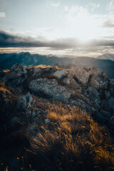 The sun shines brightly through the clouds over the mountains