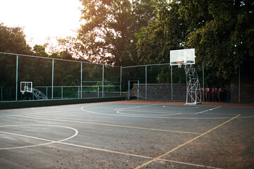 Basketball court, sports and outdoor ground for game, competition or training area with trees. Fitness, exercise and concrete arena for recreation, workout or community with asphalt, net or backboard