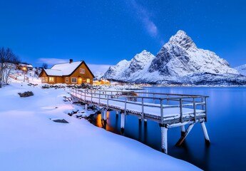 An arctic landscape with water, ice, snowy rocks, and the milky way above a frozen sea coast and snow-covered mountains at night on Lofoten Islands, Norway.