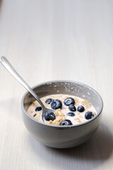 Bright and appetizing breakfast: fresh yogurt with juicy blueberries, crunchy flakes, seeds, and natural grains.