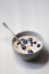 Bright and appetizing breakfast: fresh yogurt with juicy blueberries, crunchy flakes, seeds, and natural grains.
