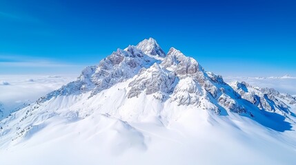 Obraz premium The snow capped peaks of snowy mountains with blue skies in winter are seen from the air in this aerial drone shot