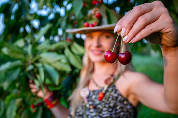 A woman is happily harvesting cherries in a vibrant orchard beneath a bright blue sky