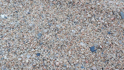 Stones and sand in the summer day. Yellow sand on the beach near a sea.