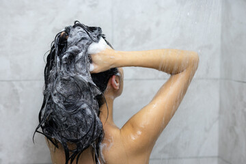 Naklejka premium Woman wash hair with shampoo and shower in bathroom
