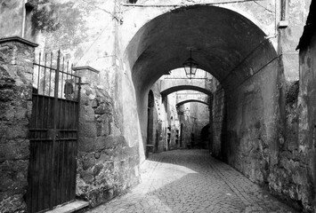 Old World narrow arched passageway in the 1970s in Orvieto, Italy in black and white