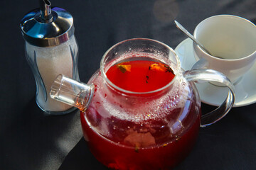 Red hot fruit tea brewed in a glass teapot