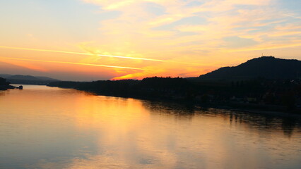 Fototapeta premium Oranger Himmel spiegelt sich in der Donau, bei Melk