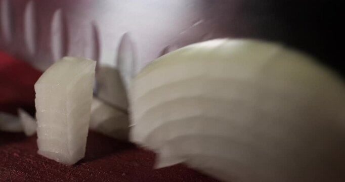 Chef preparing meal, chopping onion with a knife on a cutting board. Close up