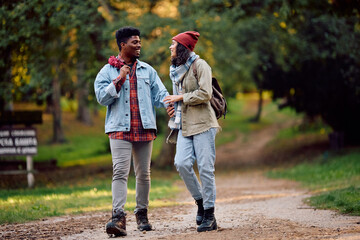 Happy multiracial couple communicating while walking in nature during autumn.