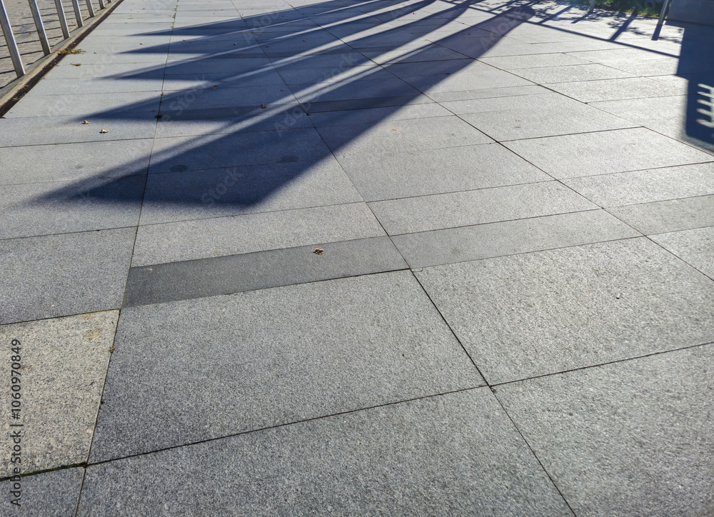 Poster sunlit pavement showing shadows, creating an abstract pattern. ideal for backgrounds or architectura