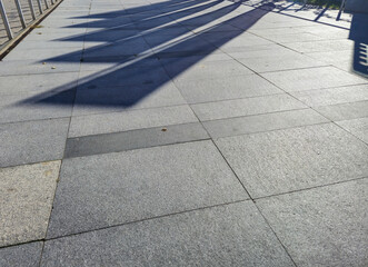 Fototapeta premium Sunlit pavement showing shadows, creating an abstract pattern. Ideal for backgrounds or architectural projects.