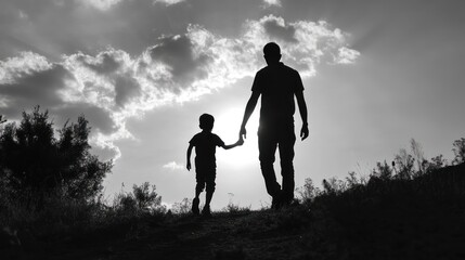 Fototapeta premium A silhouette of a parent and child walking hand in hand against a cloudy sky.