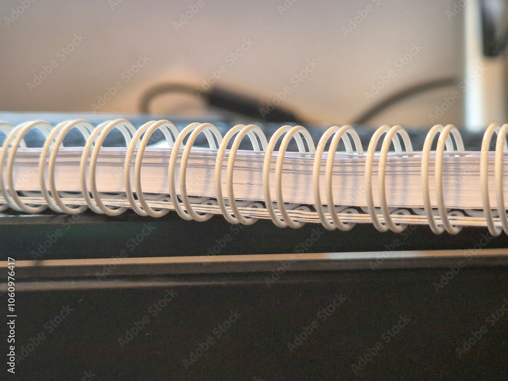 Aufkleber close-up of a wire-bound notebook resting on a desk, showcasing its spiral binding and clean pages. 