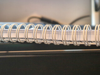 Close-up of a wire-bound notebook resting on a desk, showcasing its spiral binding and clean pages....