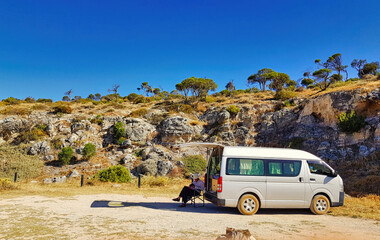 Senior man camping with a small motor home in front of a cliff at the Western Australian coast. Camping ground Cliff Head, south of Dongara, on the Indian Ocean Drive
