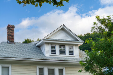 Gabled roof dormer and brick chimney of a house in Brighton, Massachusetts, USA