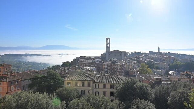 Scorcio panoramico di Perugia con alcune sue chiese e con dietro la nebbia sulla valle umbra
