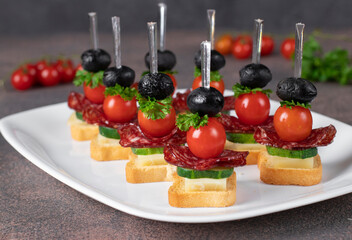 Canape with cherry tomatoes, sausage, cheese and black olives