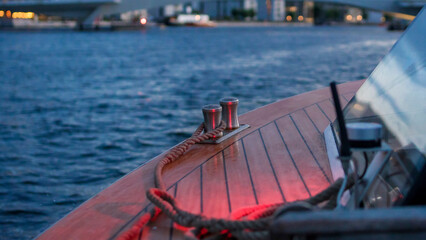 Rope on the wooden deck of a sailing yacht at sunset in a capital city. Concept of sailing, tourism and fishing.