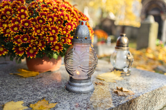 Tombstones decorated with colorful seasonal chrysanthemum flowers in cemetery during religious christian traditional autumnal event at a cemetery in Poland during All Saints Day, Zaduszki day, and Day