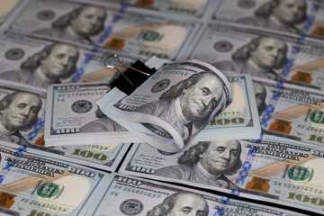 100 dollar banknotes with binder clip on dollars background