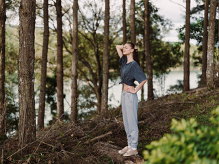 Confident young woman standing in a serene forest, enjoying nature She wears comfortable clothes, exuding a sense of peace and connection with the environment