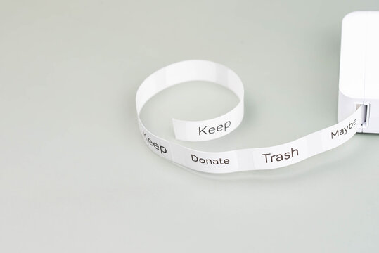 Label printer producing decluttering labels for organizing home spaces. Labels read Keep, Donate, Trash, and Maybe, as categories for effective sorting. Organized, clutter-free home environment.