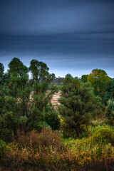 Landscape photography on the field with big and smooth clouds in the sky,Stormy weather on the picture.Big blue clouds iver the forest nd field, morning landscape in the woodlands.Aurumn blue hour,