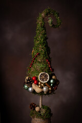 Fototapeta premium Christmas tree decoration made of moss with ornaments, dried oranges, nuts and pine cones 