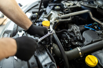 Mechanic working on an engine with tools in a workshop during daytime, focusing on maintenance and repairs