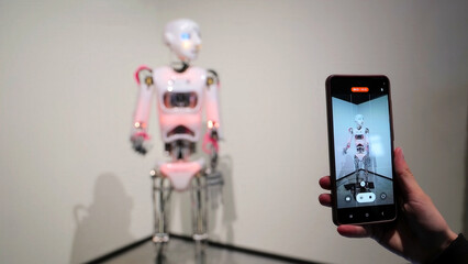 Robot Captured Through Smartphone Lens in Modern Exhibit. A humanoid robot is viewed through a...