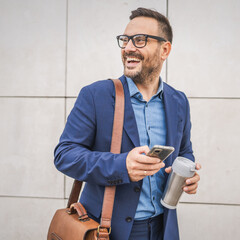Adult businessman stand in front white wall and use mobile phone