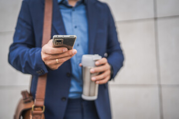 close up of unknown adult man hold mobile phone and thermos outdoor