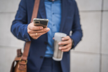 close up of unknown adult man hold mobile phone and thermos outdoor