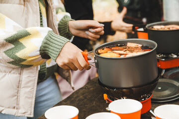 Delicious hot mulled wine in a pan on the stove, close-up. A girl prepares mulled wine at a picnic.