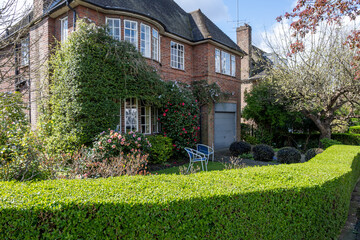 Walking on streets of North London, red brick houses and flowering gardens in spring, city life, wealthy neighbourhoods in London, UK