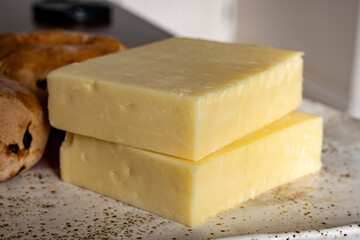 Block of aged cheddar cheese, the most popular type of cheese in United Kingdom and USA, natural cheese from cow milk