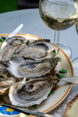Plate with fresh live oysters with citron, bread, butter and white wine served at restaurant in oyster-farming village, Arcachon bay, Gujan-Mestras port, France
