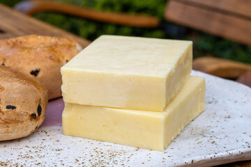 Block of aged cheddar cheese, the most popular type of cheese in United Kingdom and USA, natural cheese from cow milk