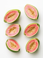 Close up of a green and pink fruit with a white background. The fruit is cut in half and has a pink interior